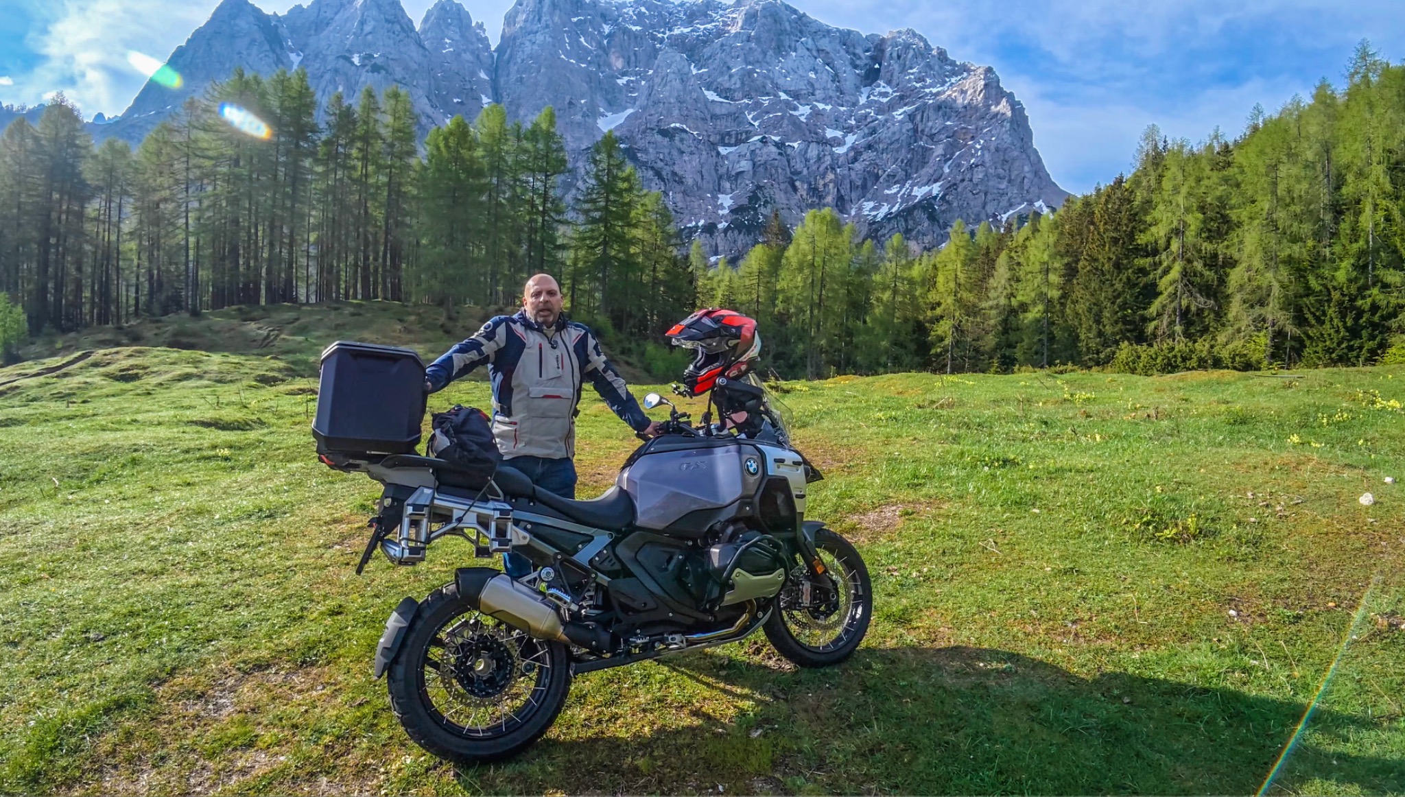 Nadeem with his BMW motorcycle in a grassy mountain clearing